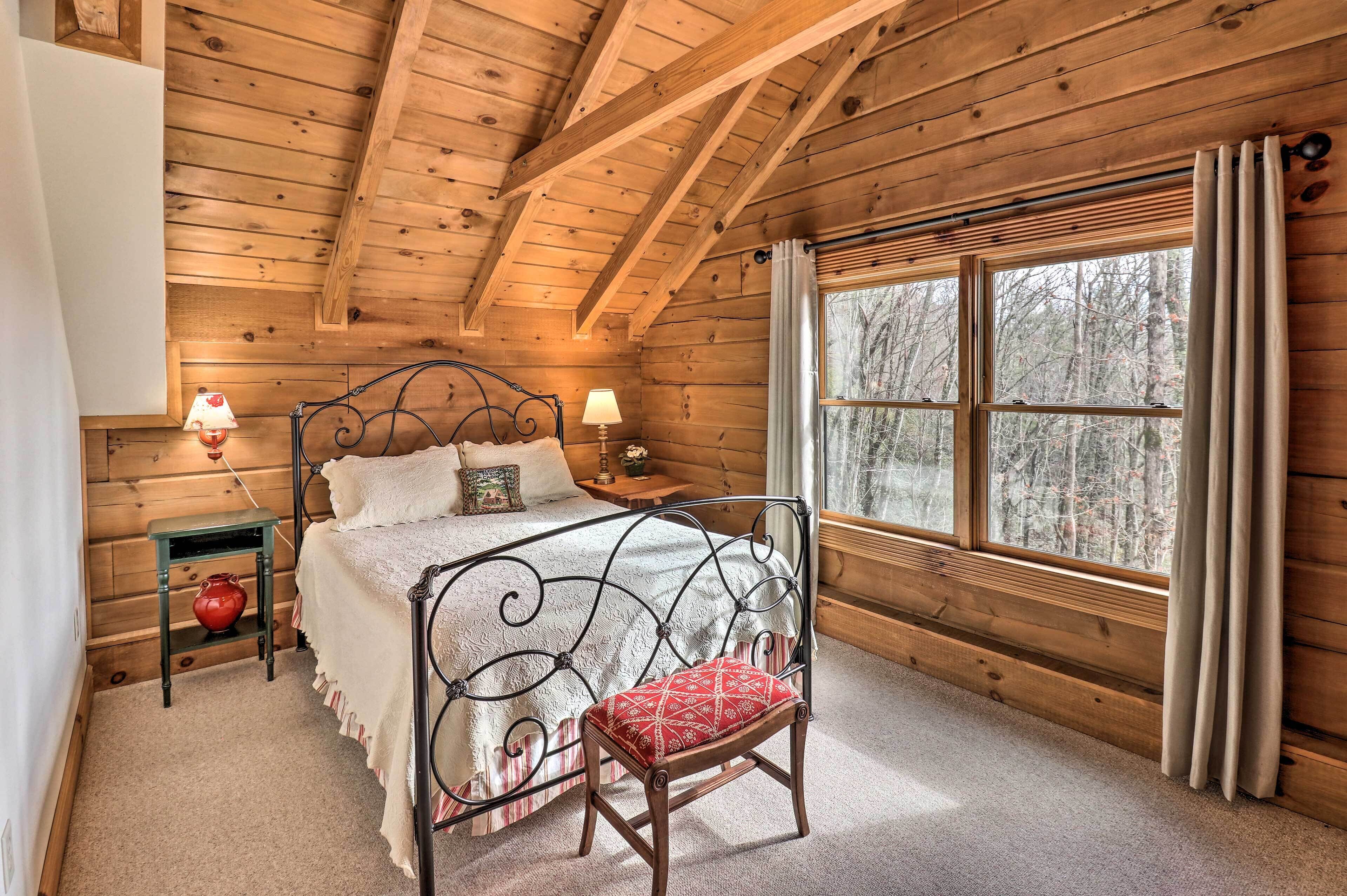 A cozy wooden cabin bedroom with a bed, bedside lamps, and a window with curtains.