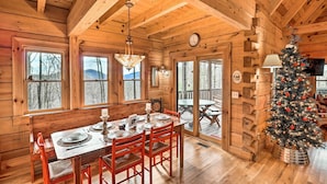 A wooden cabin interior with a dining table set for four, a Christmas tree, and large windows. - Private Sapphire Valley Resort Cabin w/ Mtn Views! (Sapphire)