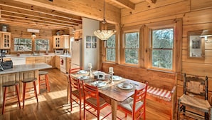 A wooden cabin interior with a dining area, kitchen, and large windows. - Private Sapphire Valley Resort Cabin w/ Mtn Views! (Sapphire)