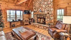 A cozy cabin interior with a stone fireplace, wooden walls, and a comfortable seating area. - Private Sapphire Valley Resort Cabin w/ Mtn Views! (Sapphire)