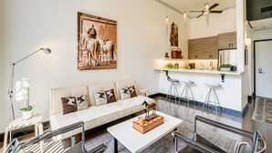 A modern living room with a sofa, coffee table, and a painting of horses.