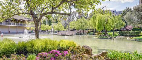 Un parc paisible avec un étang, une végétation luxuriante et un kiosque.