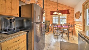 Une cuisine dotée de meubles en bois, d’un réfrigérateur en acier inoxydable, d’une machine à café et d’un coin repas avec une table et des chaises.
