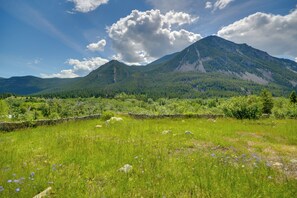 Un paysage montagneux avec un mur de pierre au premier plan et un ciel dégagé.