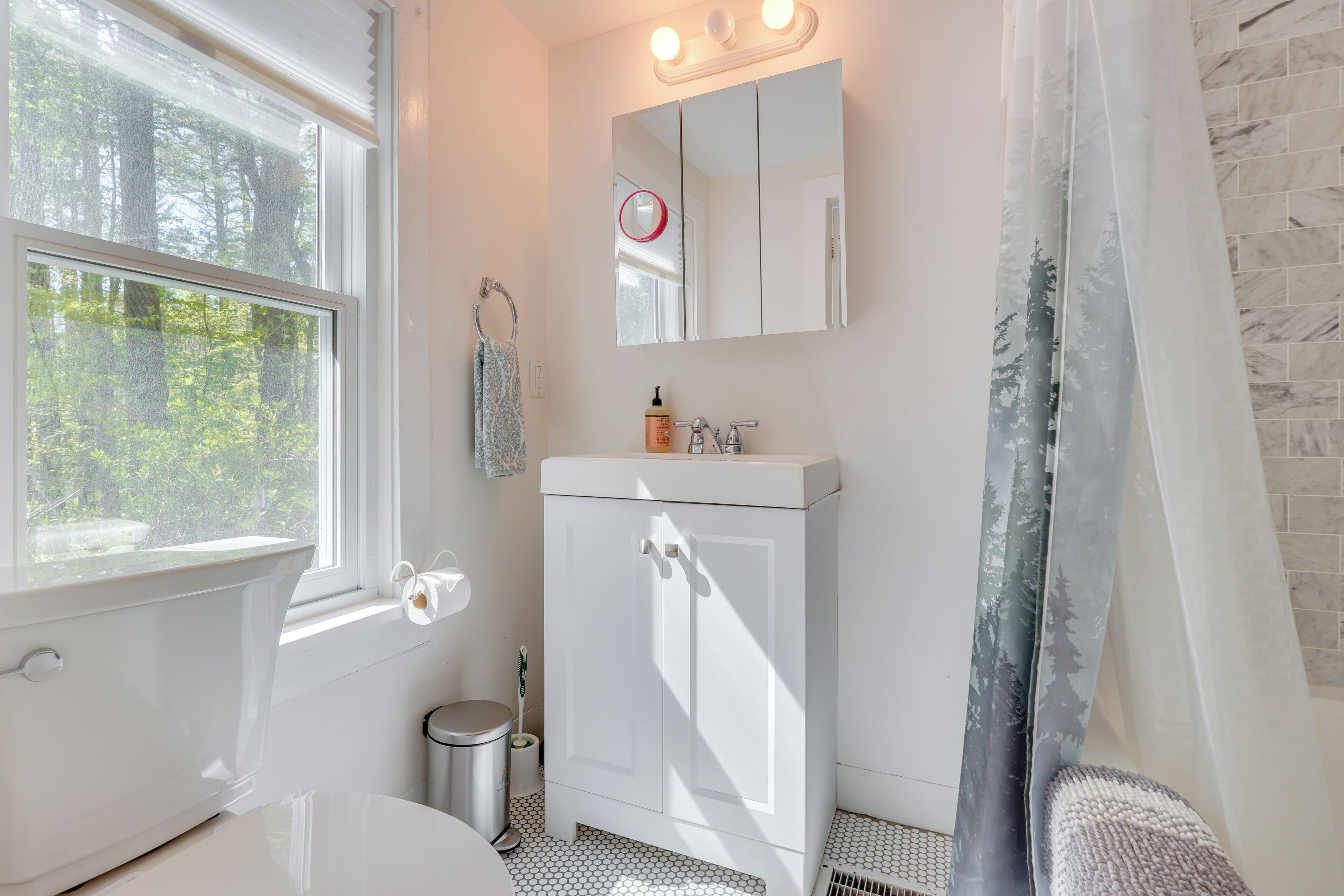 A bathroom with a toilet, sink, and mirror.