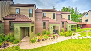 A row of townhouses with a green front door, a small garden area with various plants, and a clear sky. - Lutsen Mountains Retreat w/ Resort Amenities! (Lutsen)