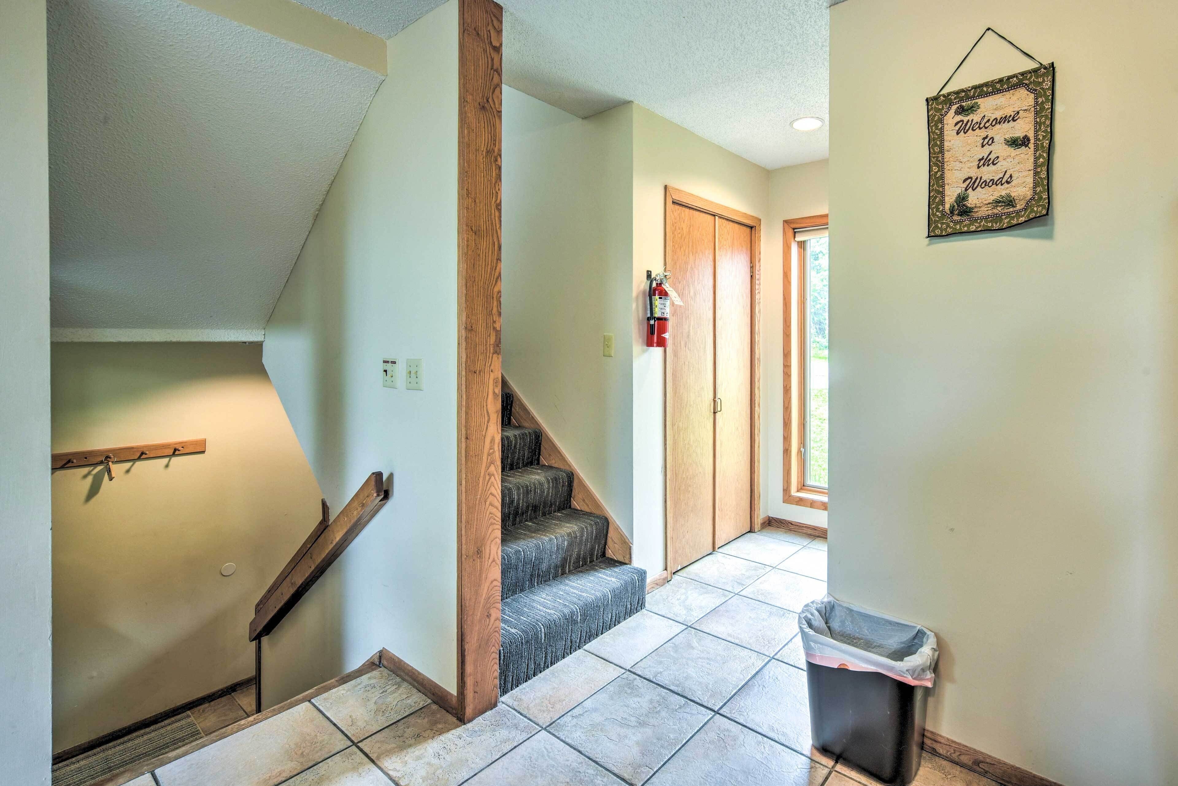 A staircase with wooden handrails, a fire extinguisher mounted on the wall, and a welcome sign.