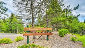 A wooden bench with a sign reading "Townhomes" in a park with trees and gravel. - Lutsen Mountains Retreat w/ Resort Amenities! (Lutsen)