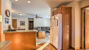 A kitchen with wooden cabinets, a refrigerator, a ceiling fan, and a dining area with a table and chairs.