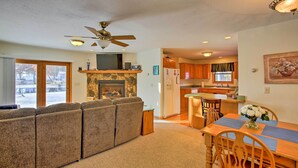 A living room with a fireplace, a dining area with a table and chairs, and a kitchen in the background.