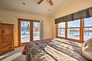 Un dormitorio con una cama grande, un aparador de madera y una ventana con vistas a un paisaje nevado.
