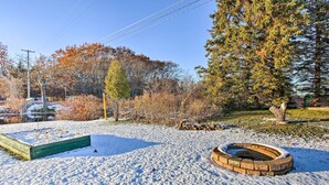 A snow-covered outdoor area with a fire pit and a wooden deck.