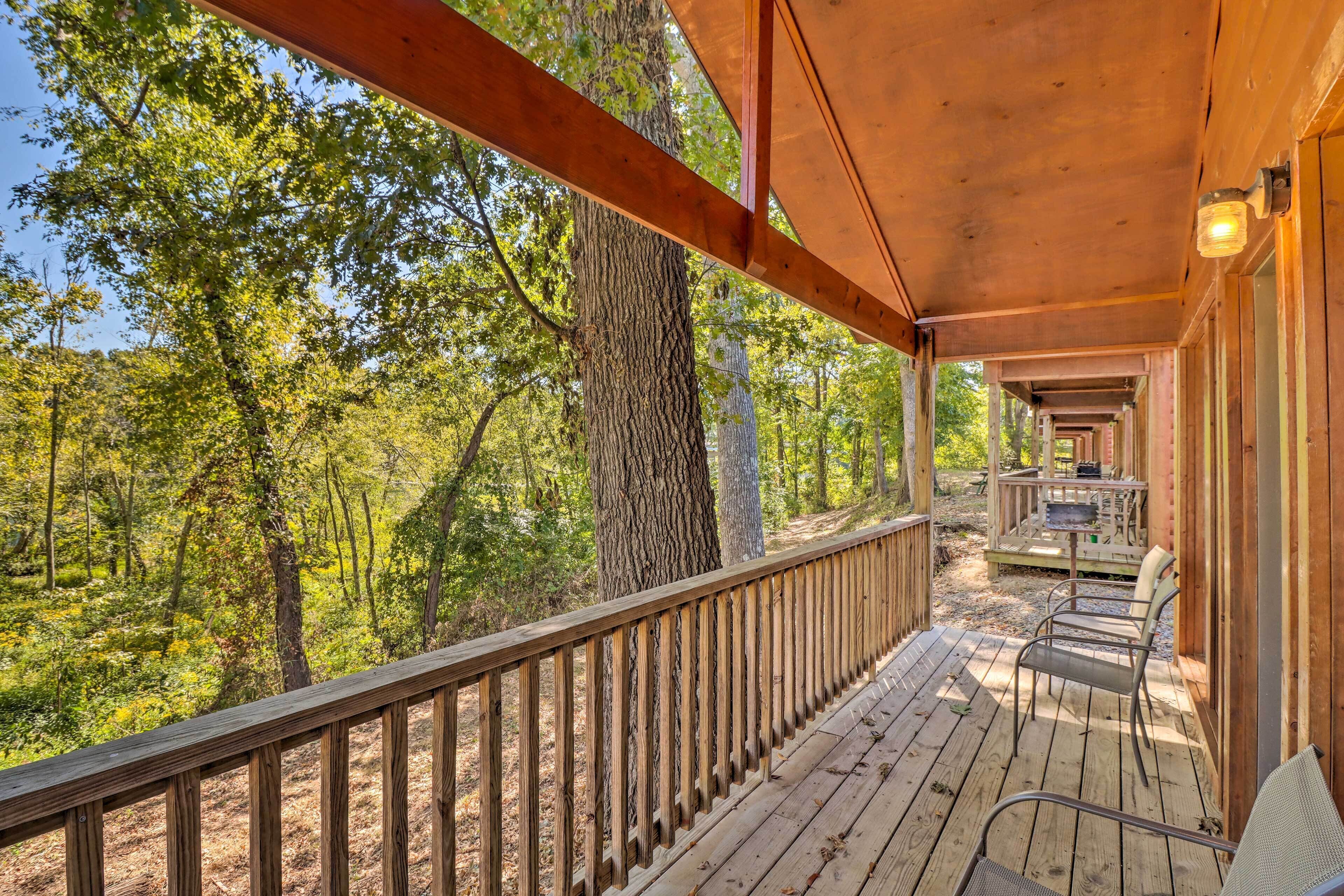 A wooden deck with a railing, overlooking a forested area.