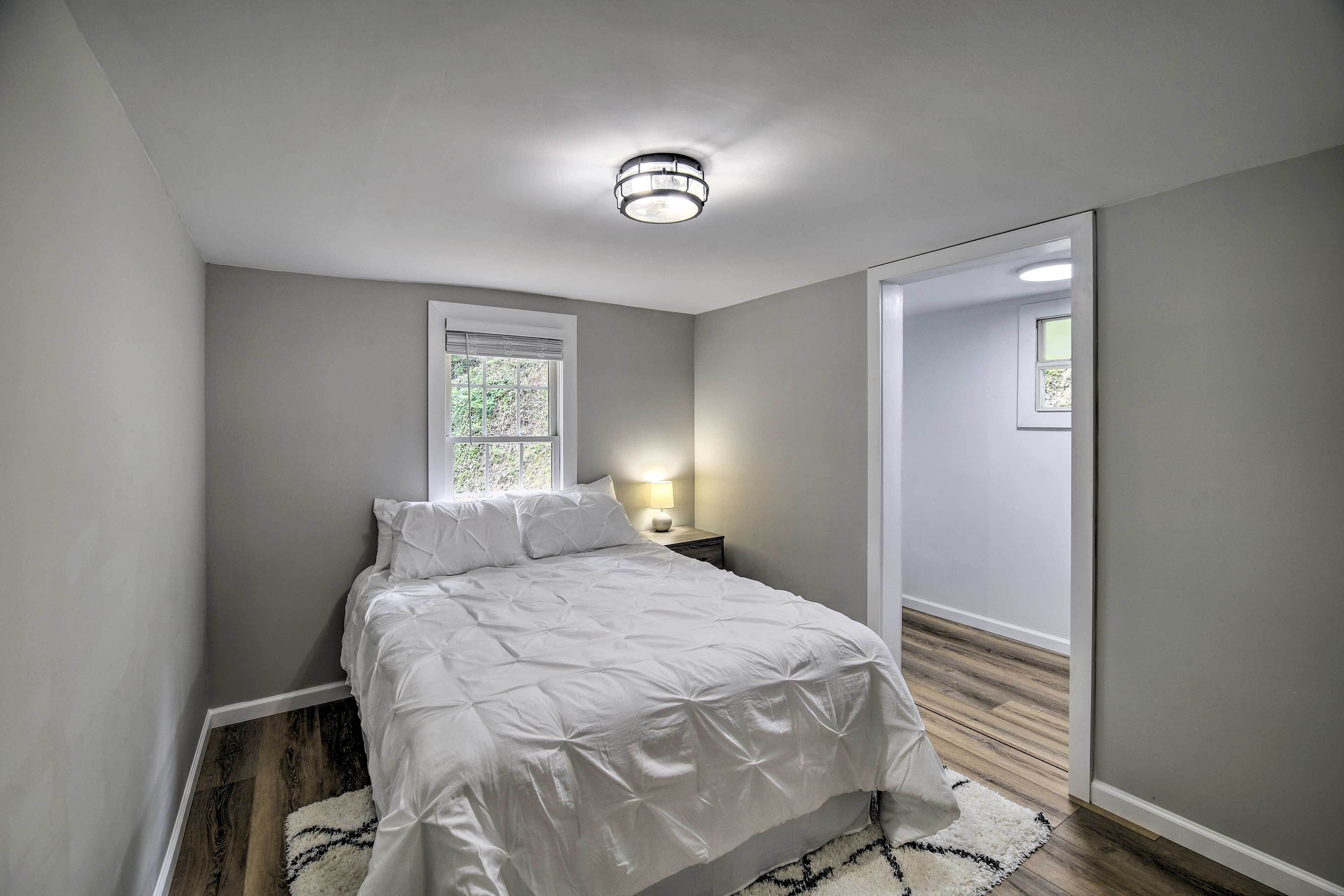 A bedroom with a bed, a nightstand, a window, and a door.