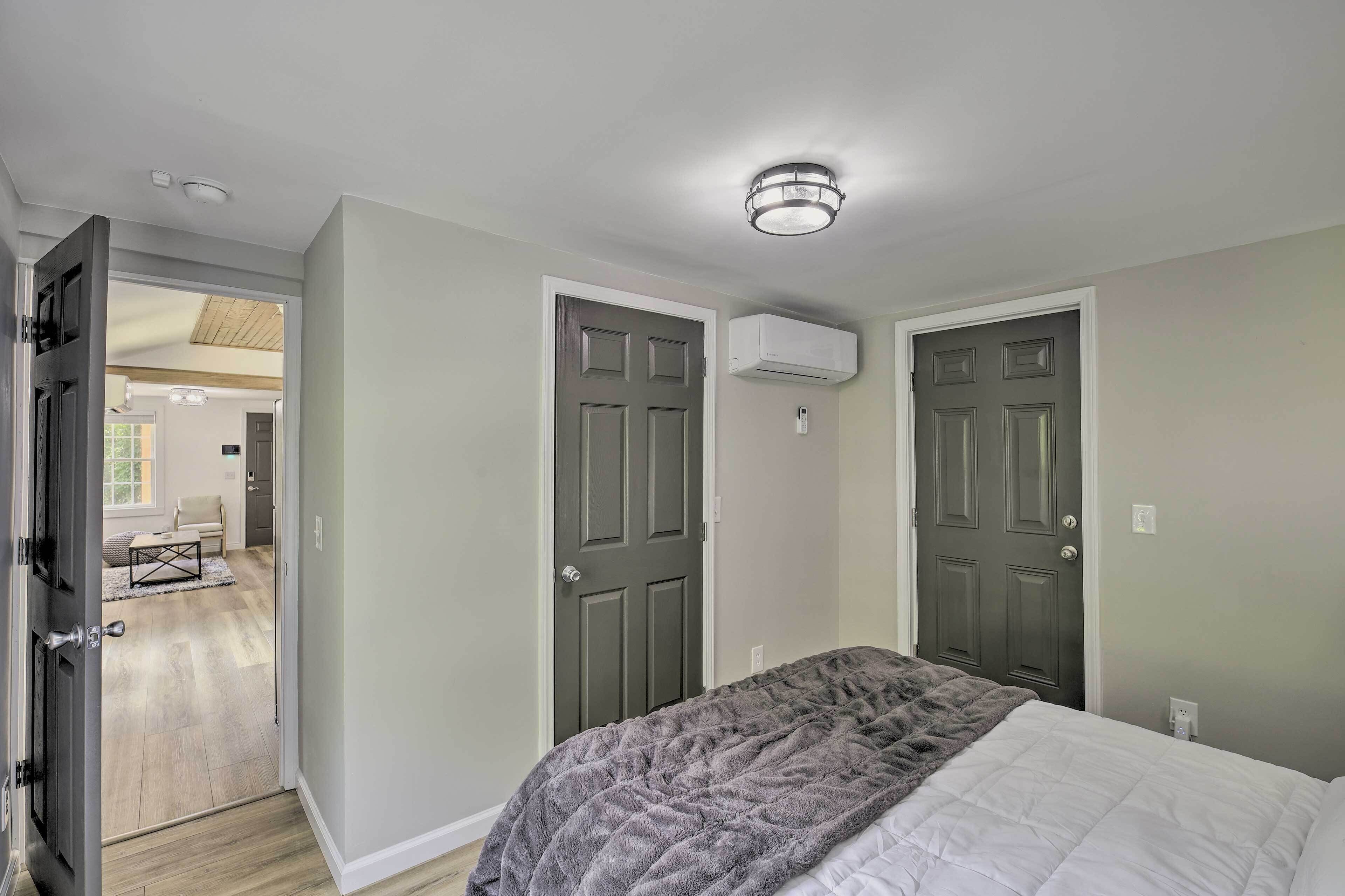 A bedroom with two doors, a bed with a gray blanket, and a ceiling light fixture.