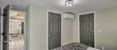 A bedroom with two doors, a bed with a gray blanket, and a ceiling light fixture.