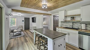 A modern kitchen with a wooden ceiling, white cabinetry, and a central island with stools. - Updated Bristol Retreat ~ 2 Miles to Downtown! (Bristol)