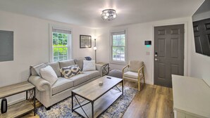 A living room with a sofa, coffee table, and chair, a door, and windows with blinds. - Updated Bristol Retreat ~ 2 Miles to Downtown! (Bristol)
