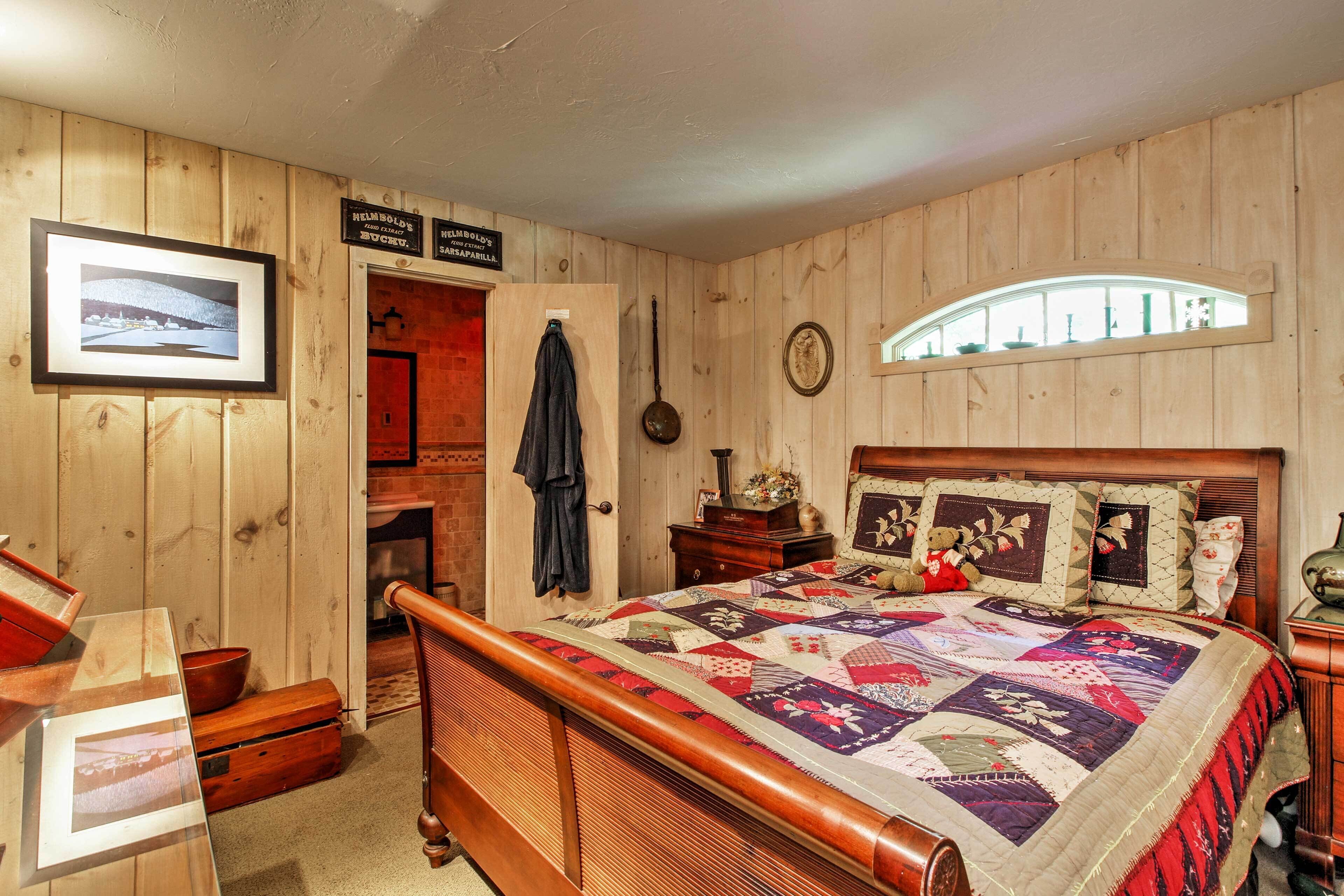 Una stanza con rivestimento in legno, un letto, un comò in legno, un quadro incorniciato e una finestra con vista.