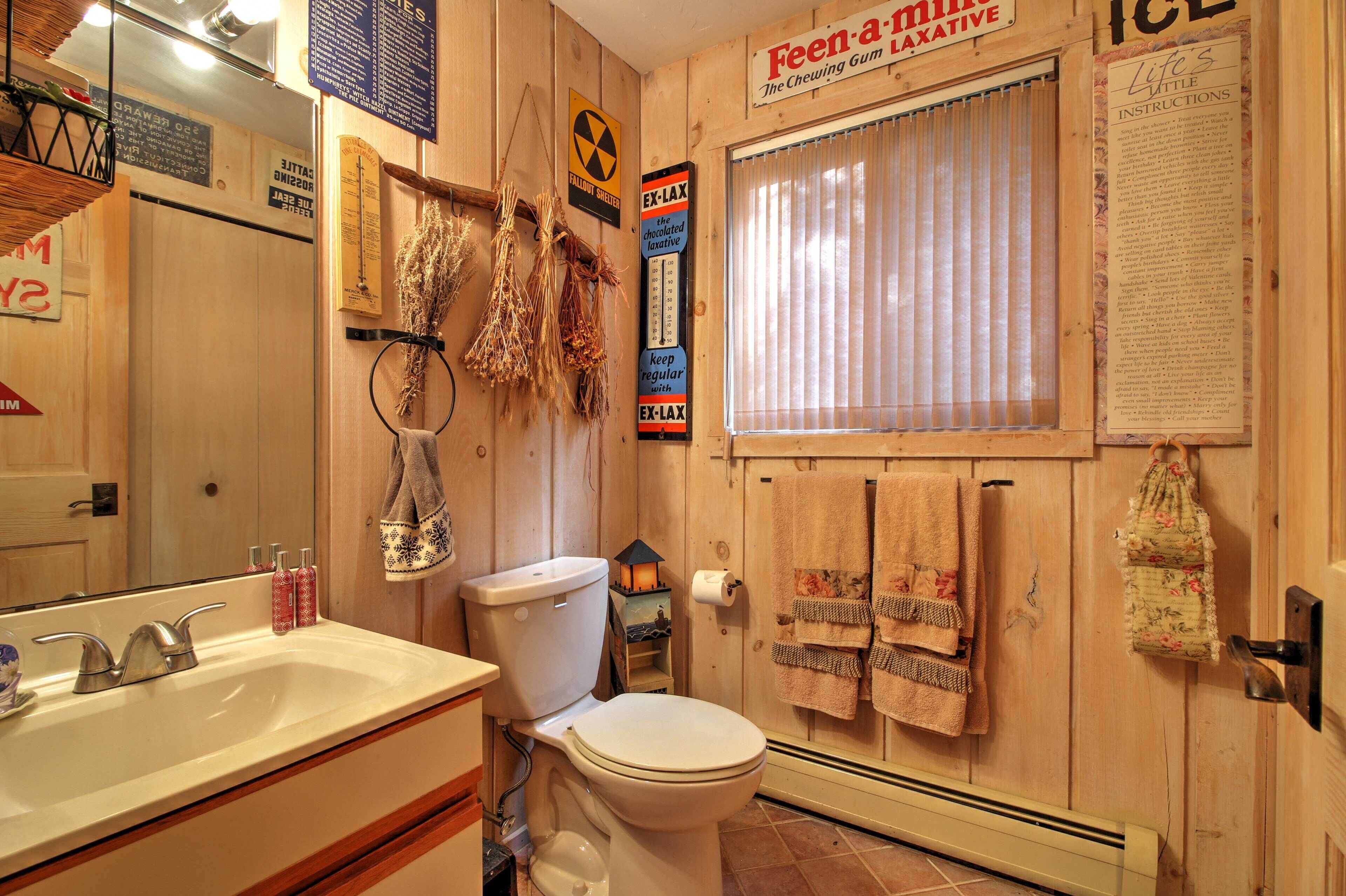 Une salle de bain avec un intérieur en bois, des toilettes, un lavabo et une fenêtre avec des stores.
