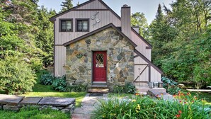 A stone house with a red door, surrounded by lush greenery and a stone pathway. - West Dover Vacation Rental w/ Hot Tub Near Mt Snow (West Dover)