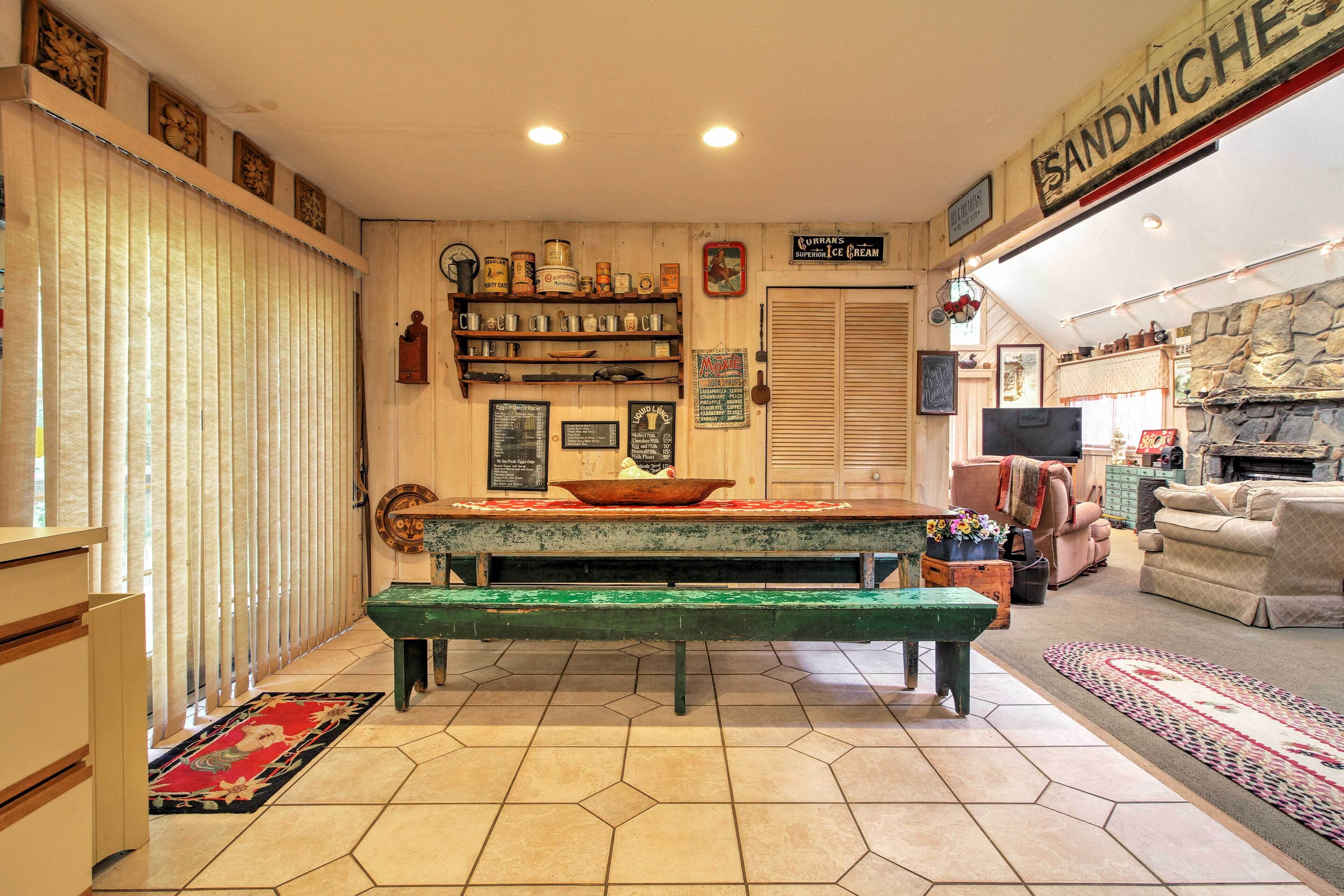 A cozy dining area with a wooden bench, a rustic wall with shelves of jars and a sign for sandwiches.