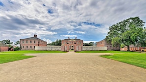 A large brick building with a symmetrical facade, a central entrance, and a paved courtyard.