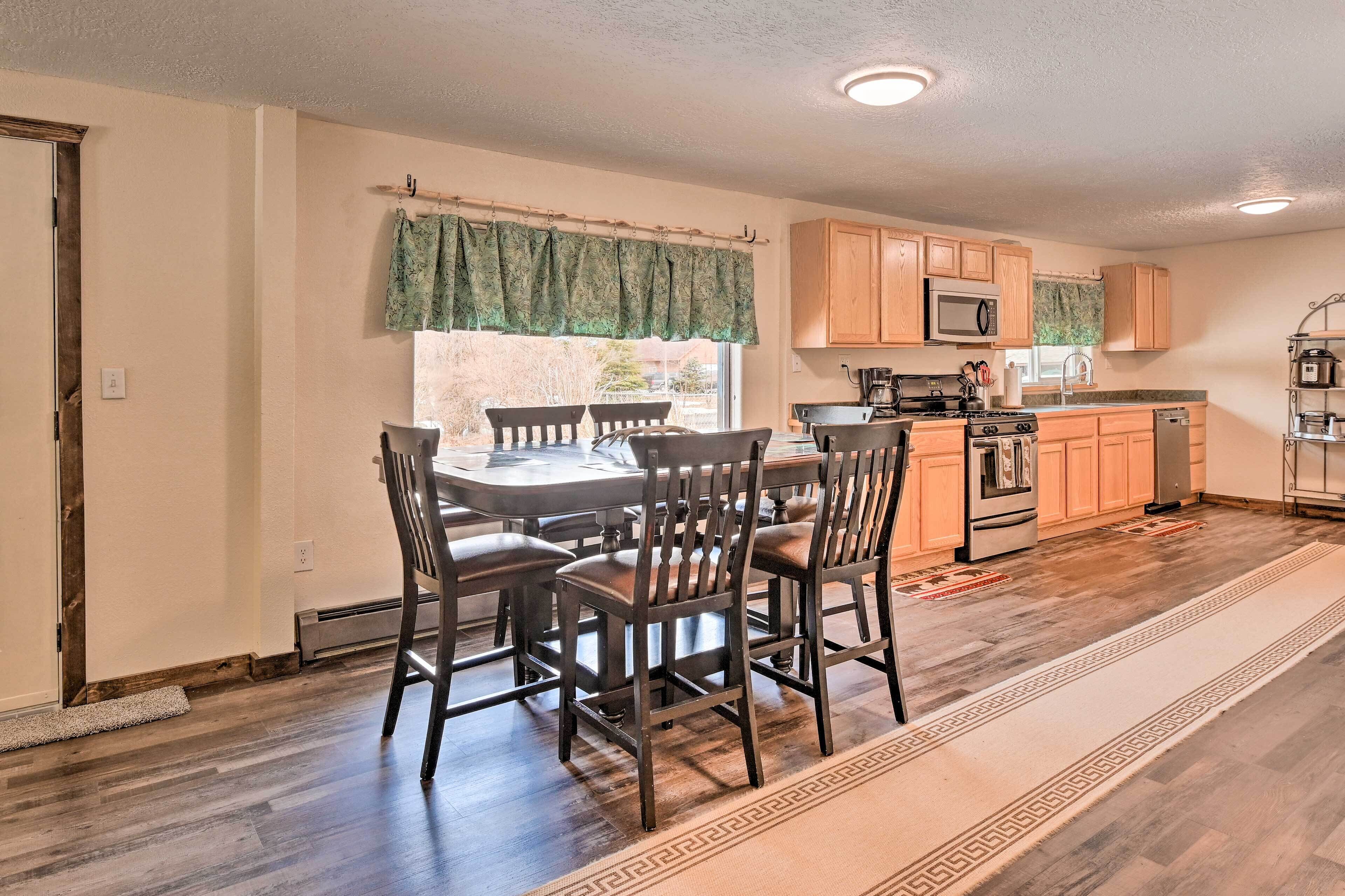 A kitchen with wooden cabinets, a microwave, a stove, and a dining area with a table and chairs.
