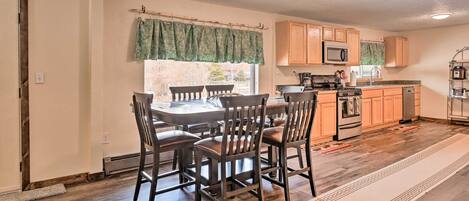 A kitchen with wooden cabinets, a microwave, a stove, and a dining area with a table and chairs.