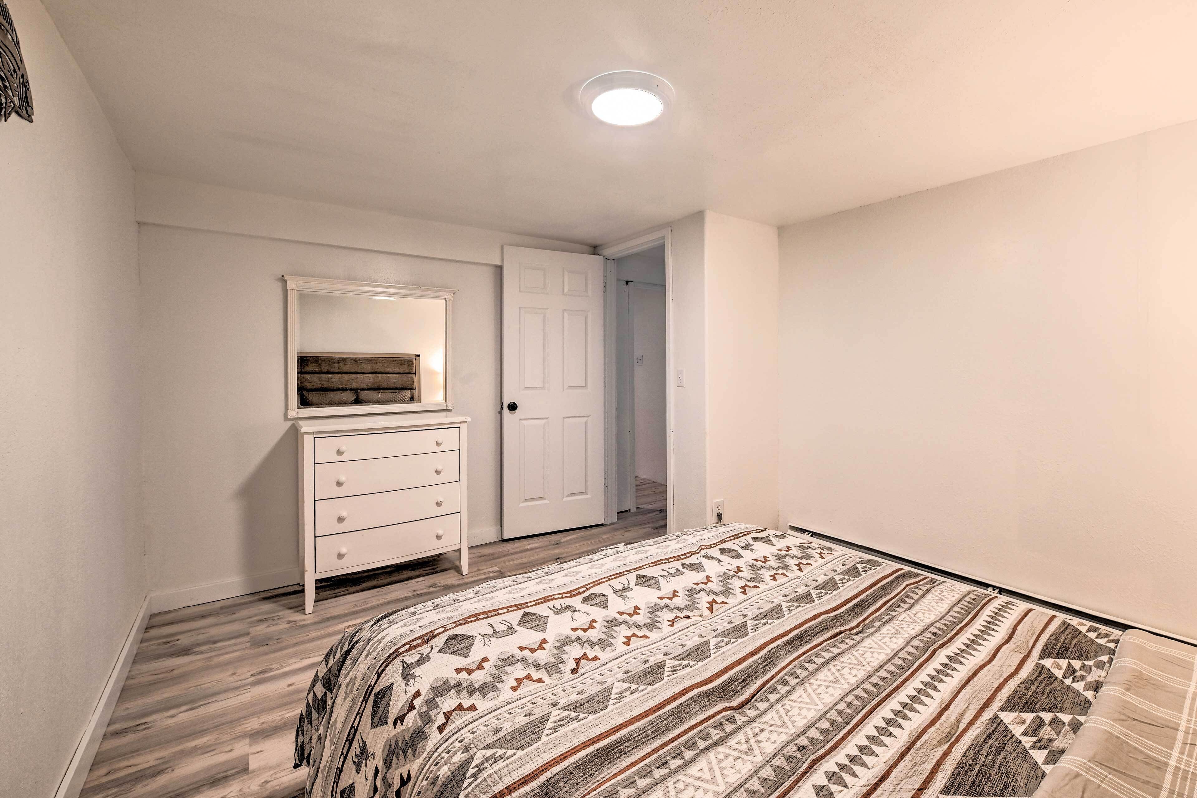 A bedroom with a bed, dresser, and door.