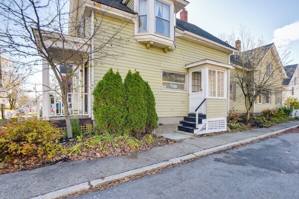 A two-story house with a front porch, a small staircase, and a well-maintained garden. - Charming Saco Apartment ~ 4 Mi to the Beach! (Saco)