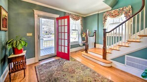 A foyer with a wooden staircase, a red door, and a potted plant. - Edenton Vacation Rental w/ Patio: Walk Downtown (Edenton)