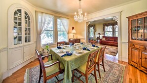 A dining room with a large table set for a meal, surrounded by wooden chairs and a chandelier. - Edenton Vacation Rental w/ Patio: Walk Downtown (Edenton)