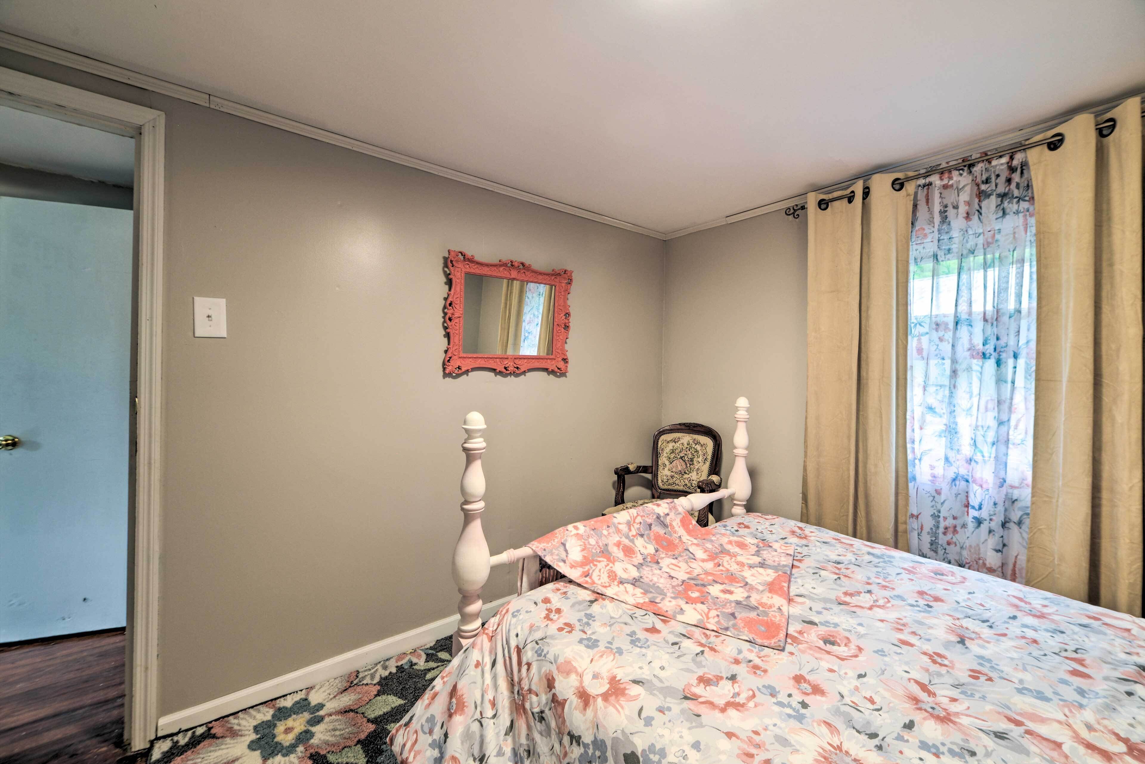 Un dormitorio con cama, espejo, silla y puerta.
