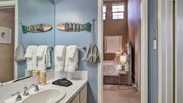 A bathroom with a sink, multiple towels, and a mirror.