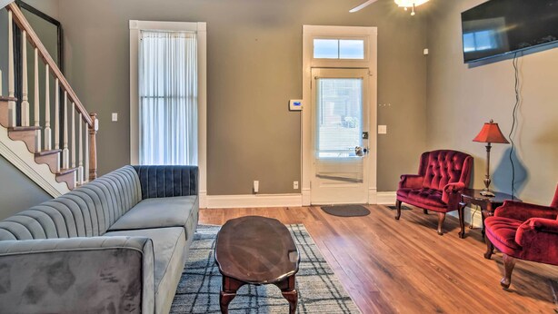 A living room with a sofa, chairs, a small stool, a ceiling fan, a TV, and a door with a window. - Stylish Vicksburg Apt w/ Porch - 2 Mi to Casino! (Vicksburg)