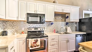 A modern kitchen with white cabinets, a black microwave, a stainless steel stove, and a dishwasher. - Stylish Vicksburg Apt w/ Porch - 2 Mi to Casino! (Vicksburg)