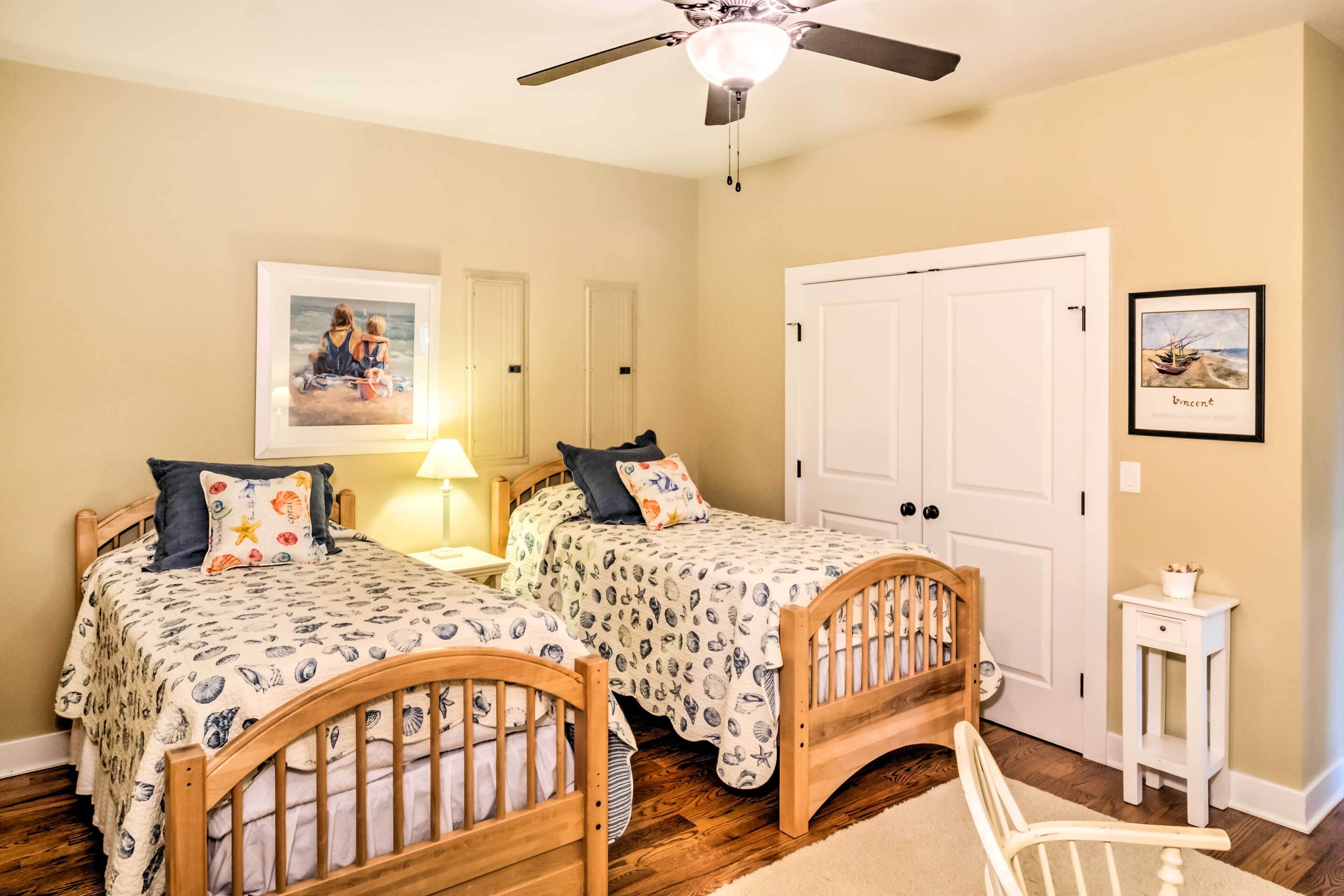 A bedroom with two wooden beds, a ceiling fan, a door, and a small table.
