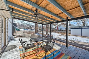 A covered patio with a table and chairs, a ceiling fan, and a view of the backyard.