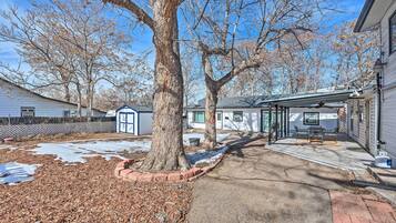 A residential property with a covered patio, a large tree, and a snow-covered ground.