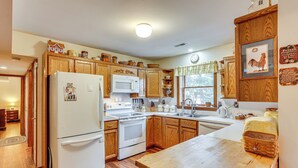 A kitchen with wooden cabinets, a refrigerator, microwave, stove, and a wooden countertop.