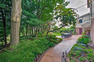 Un sendero que lleva a un edificio con mesas al aire libre y un jardín.