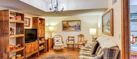 Un accogliente soggiorno con mobili in legno, una televisione e un grande quadro appeso al muro.