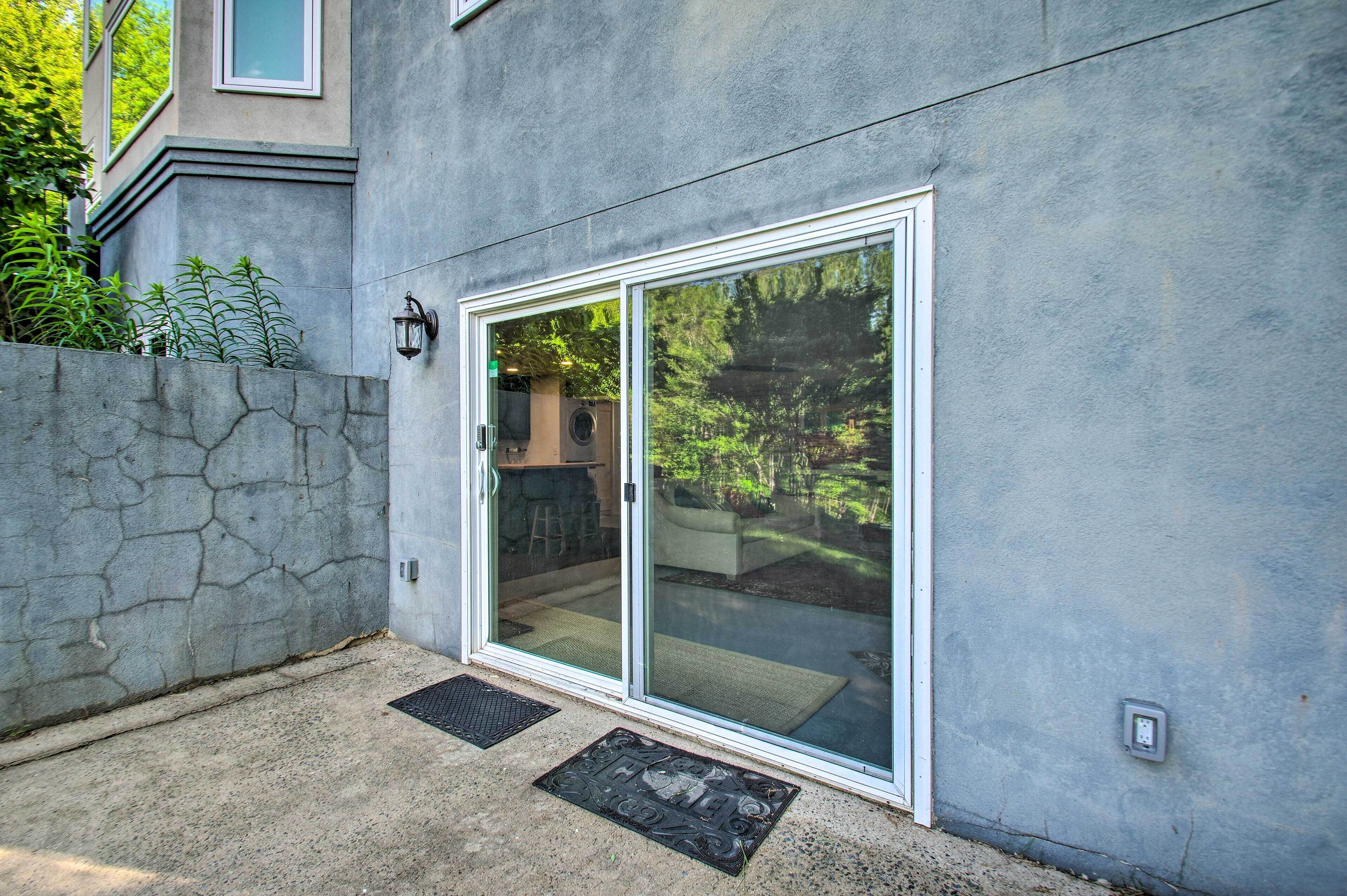 A modern house with a large sliding glass door leading to a covered patio area.
