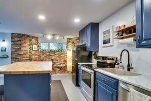 Uma cozinha moderna com parede de tijolos, eletrodomésticos de aço inoxidável e armários azuis.