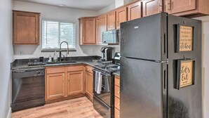 Una cocina con armarios de madera, un refrigerador negro, una estufa y un lavavajillas.