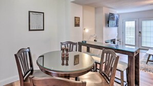Un comedor con una mesa redonda de vidrio, sillas de madera y un menú enmarcado en la pared.