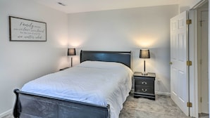 Un dormitorio con cama, dos mesitas de noche con lámparas, una lámpara de pared y una puerta.