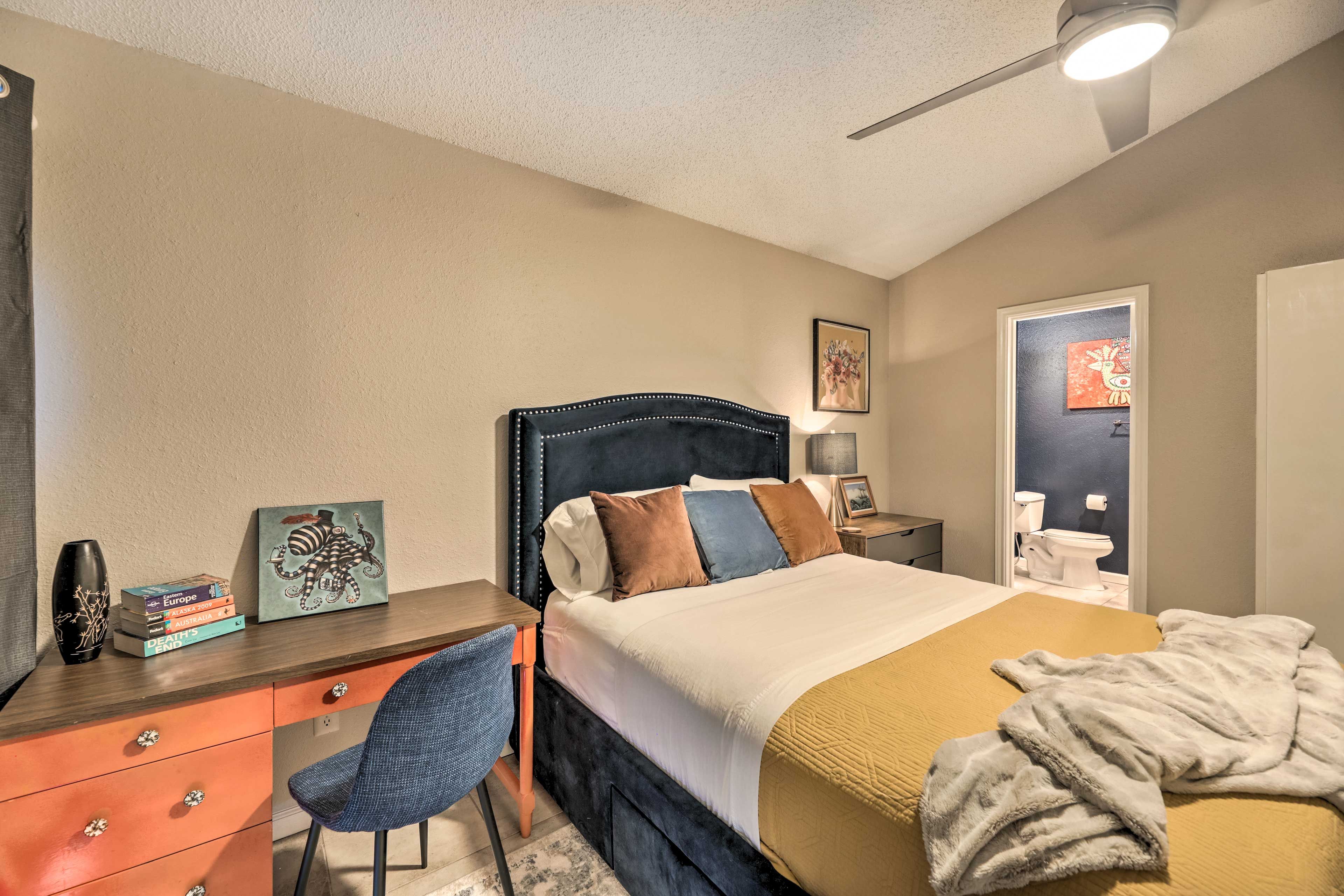 A bedroom with a bed, a desk, a chair, a dresser, and a nightstand.