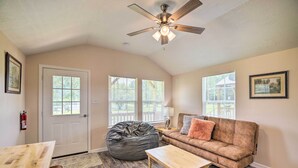 A cozy living room with a wooden table, a bean bag, a brown sofa, and a ceiling fan. - Stylish Woodville Cabin: Fishing Dock Access! (Woodville)